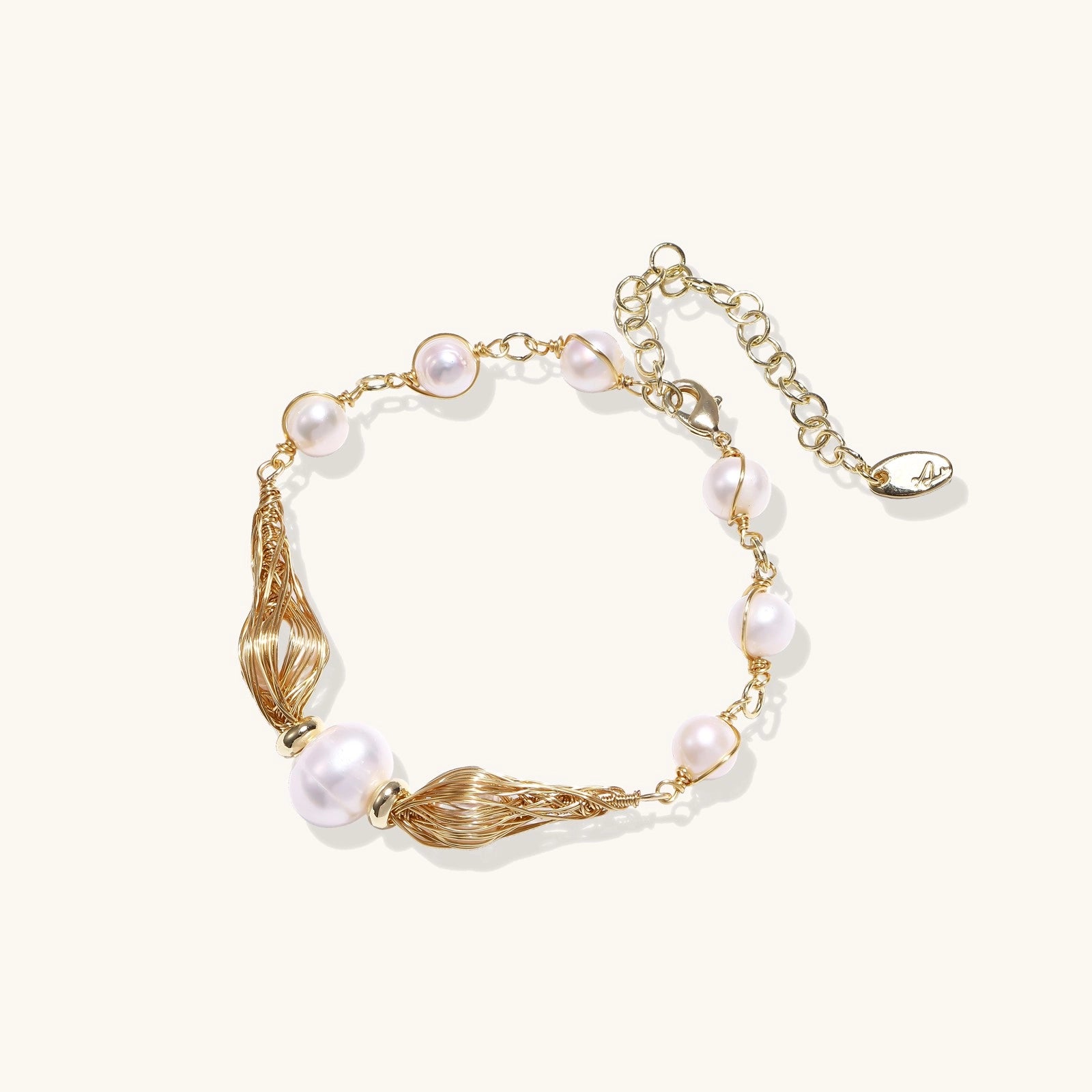 Delicate 14K gold plated bracelet with freshwater pearls and ribbed gold elements on cream background.