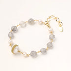 Gold-plated bracelet with white freshwater pearls and translucent grey crystals, featuring mesh-wrapped baroque pearl centerpiece