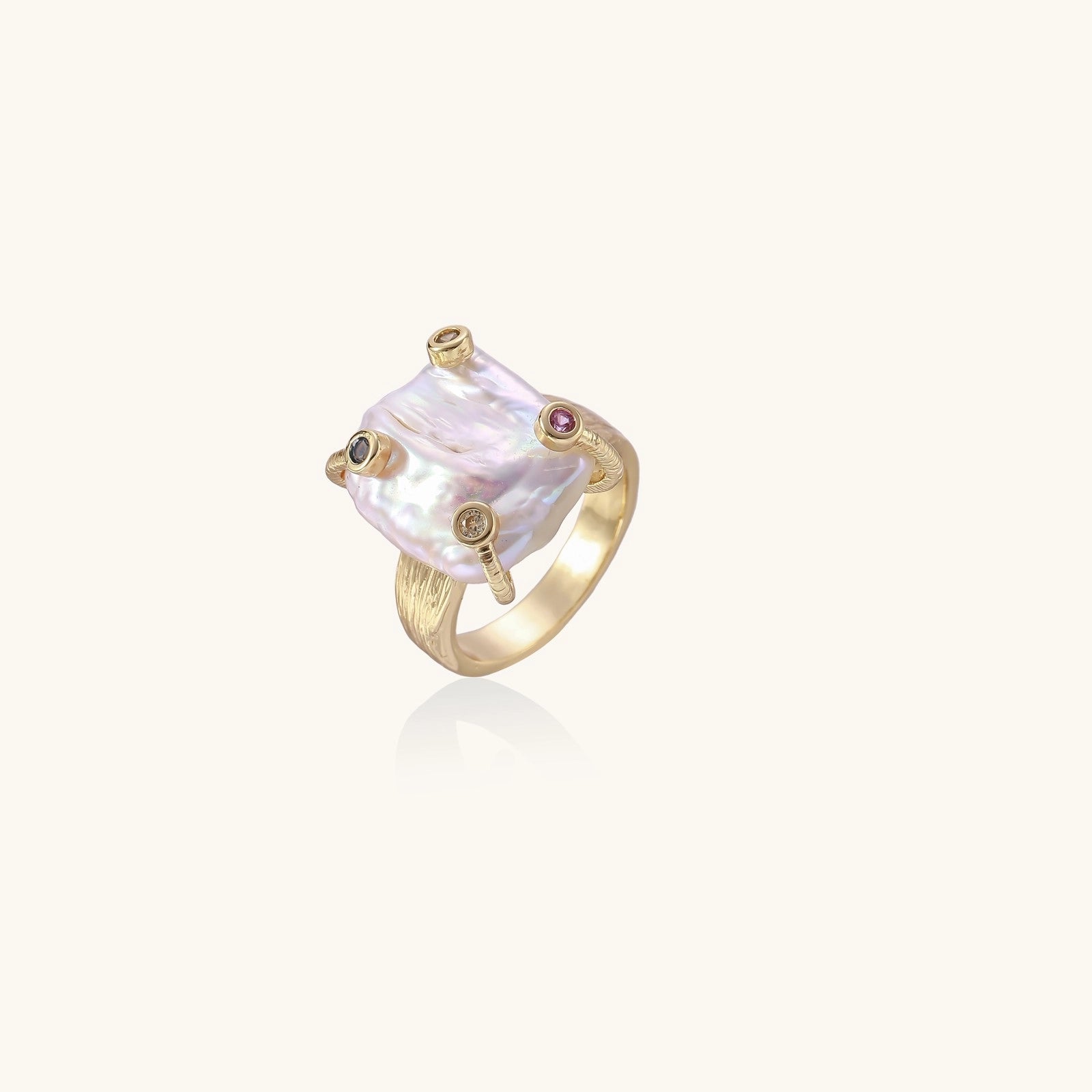 Gold-plated ring featuring large baroque freshwater pearl with small colorful gemstone accents on textured band