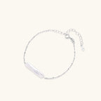 Delicate sterling silver chain bracelet with an organic white baroque pearl centerpiece on neutral background