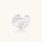 Wide sterling silver ring with flowing wave patterns and adjustable cuff design on white background.