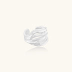 Wide sterling silver ring with flowing wave patterns and adjustable cuff design on white background.