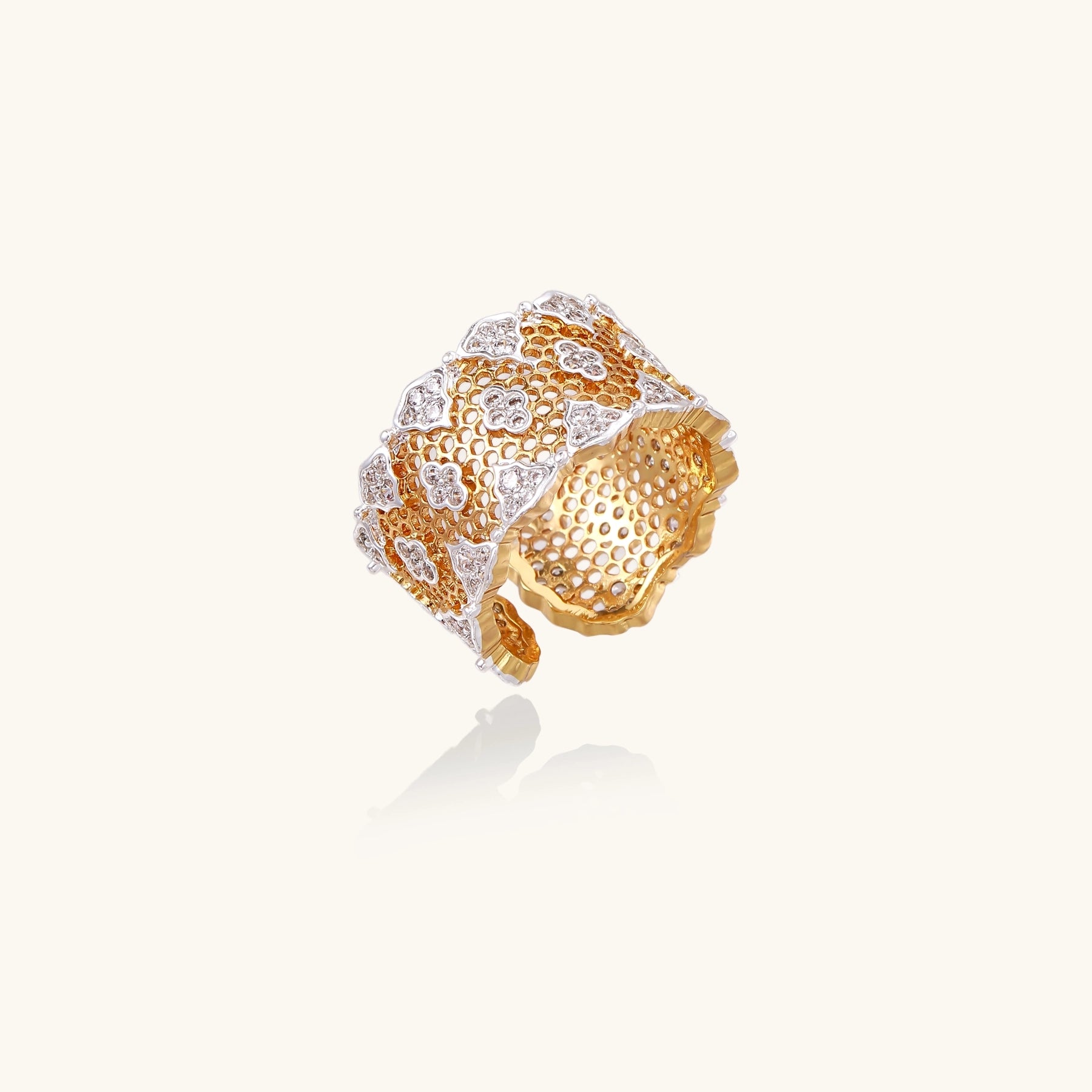 Wide gold-plated ring featuring intricate honeycomb mesh pattern with scattered zirconia stones on cream background
