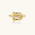 Modern gold-plated adjustable ring with safety pin design and sparkling cubic zirconia accents on white background